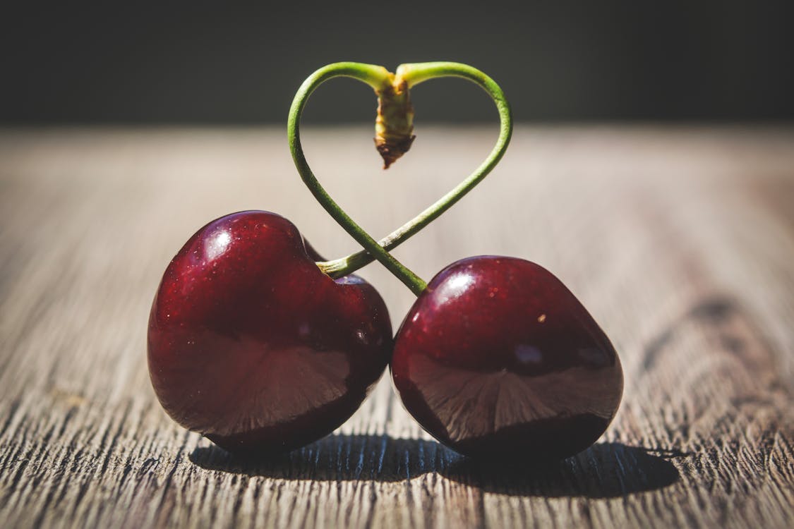 Two Red Cherries on Brown Surface