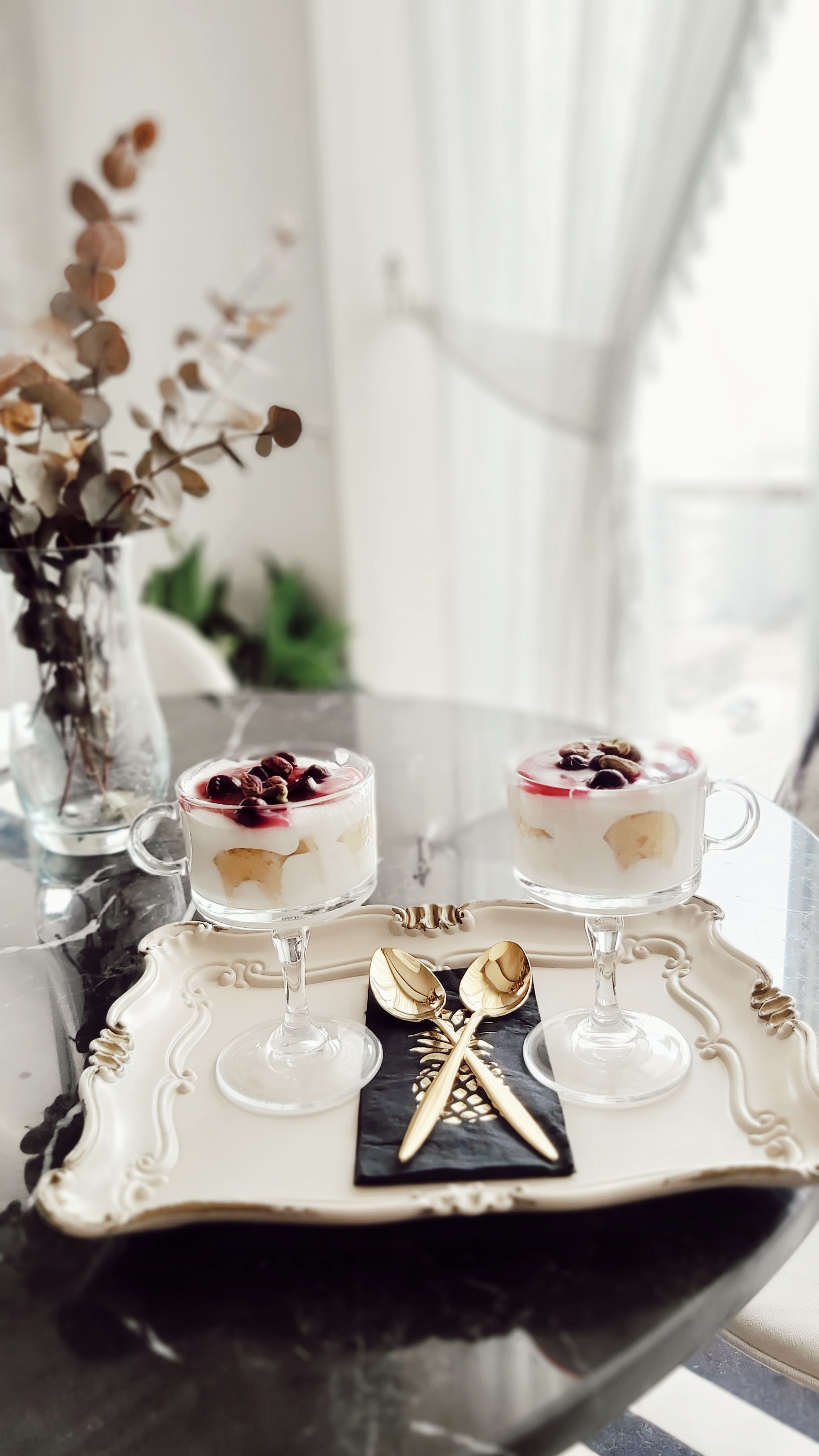 Sophisticated dessert setup featuring yogurt parfaits with berries on an ornate tray.