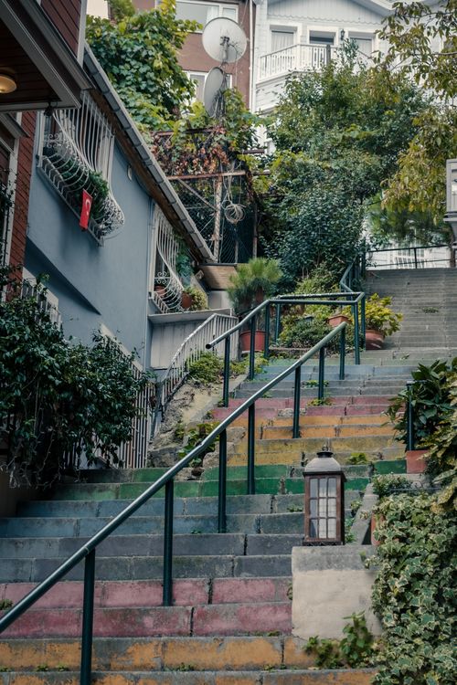 Free Vertical shot of a vibrant city staircase surrounded by greenery and urban architecture. Stock Photo