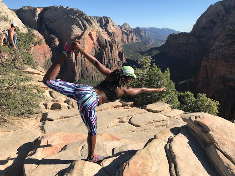 Woman Stretching On Top Of Mountain