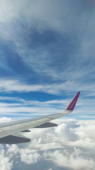 Captivating aerial view of an airplane wing over the fluffy white clouds and blue sky.