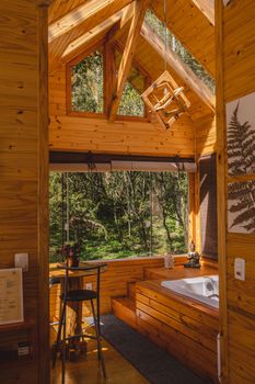 Warm wooden cabin interior with a serene forest view and natural lighting.