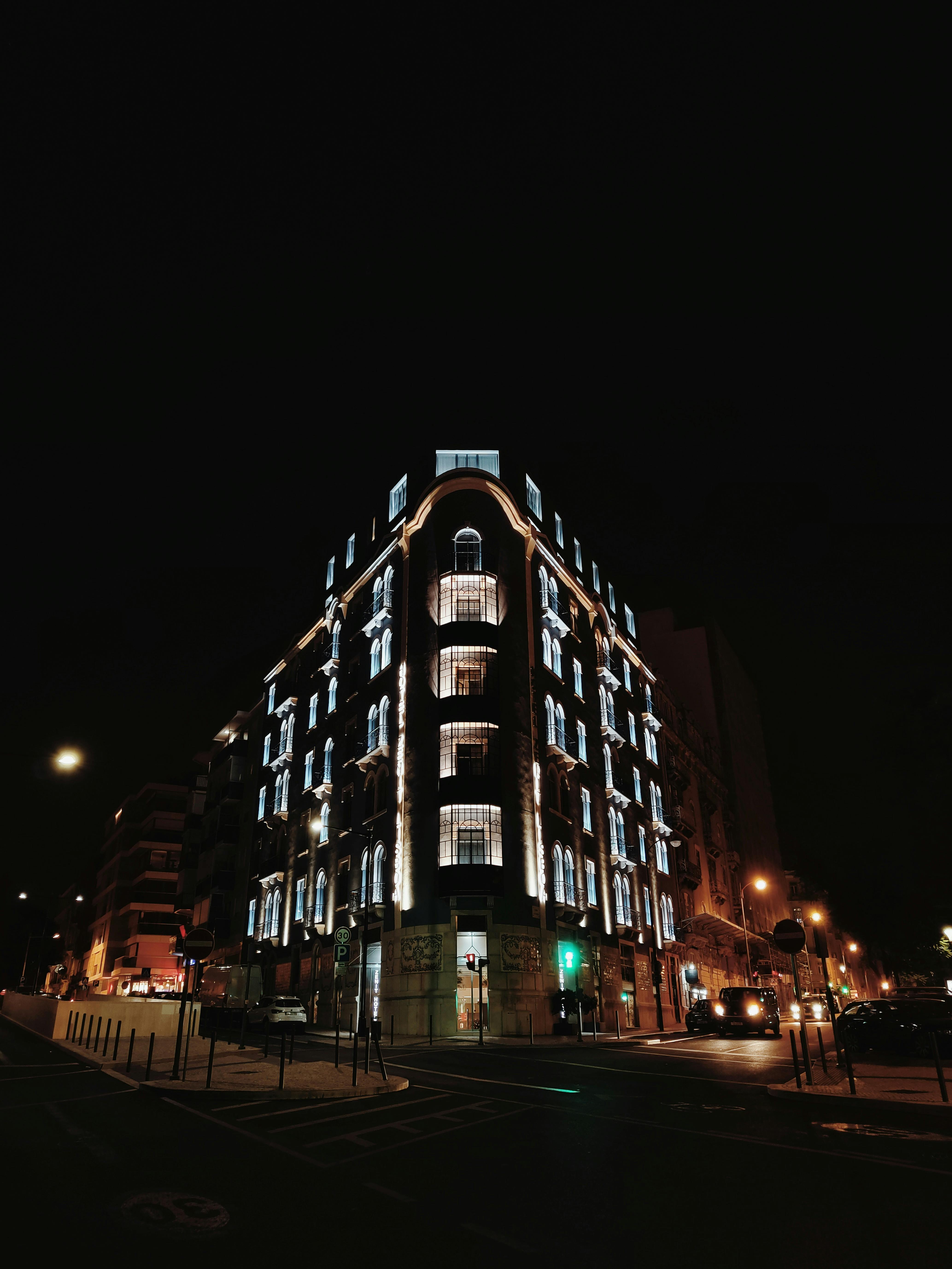 Free A striking illuminated facade of a building at night captured in a bustling city street setting. Stock Photo