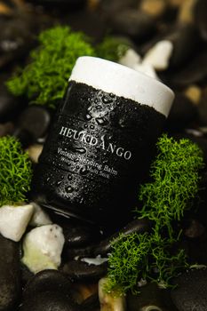 Close-up of vintage blending balm surrounded by stones and greenery, showcasing moisture and freshness.