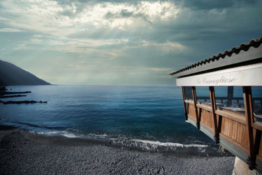 Overcast coastal view in Camogli, Liguria with La Camogliese restaurant by the sea.