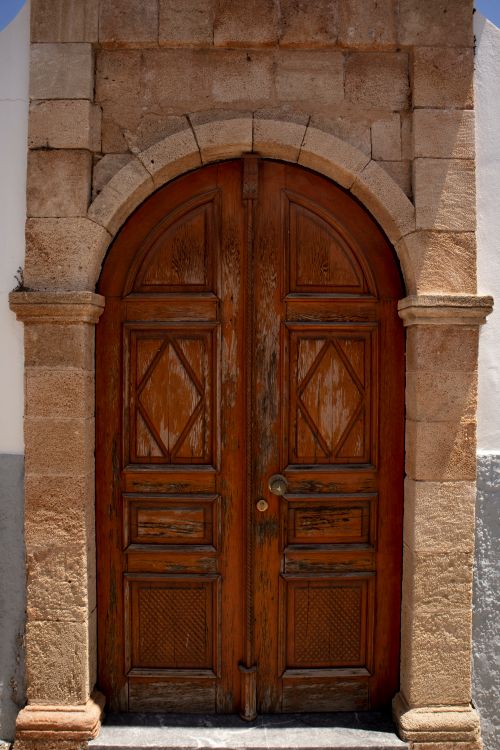 Free Vintage wooden arched door with stone frame in Rhodes, showcasing historical architecture. Stock Photo