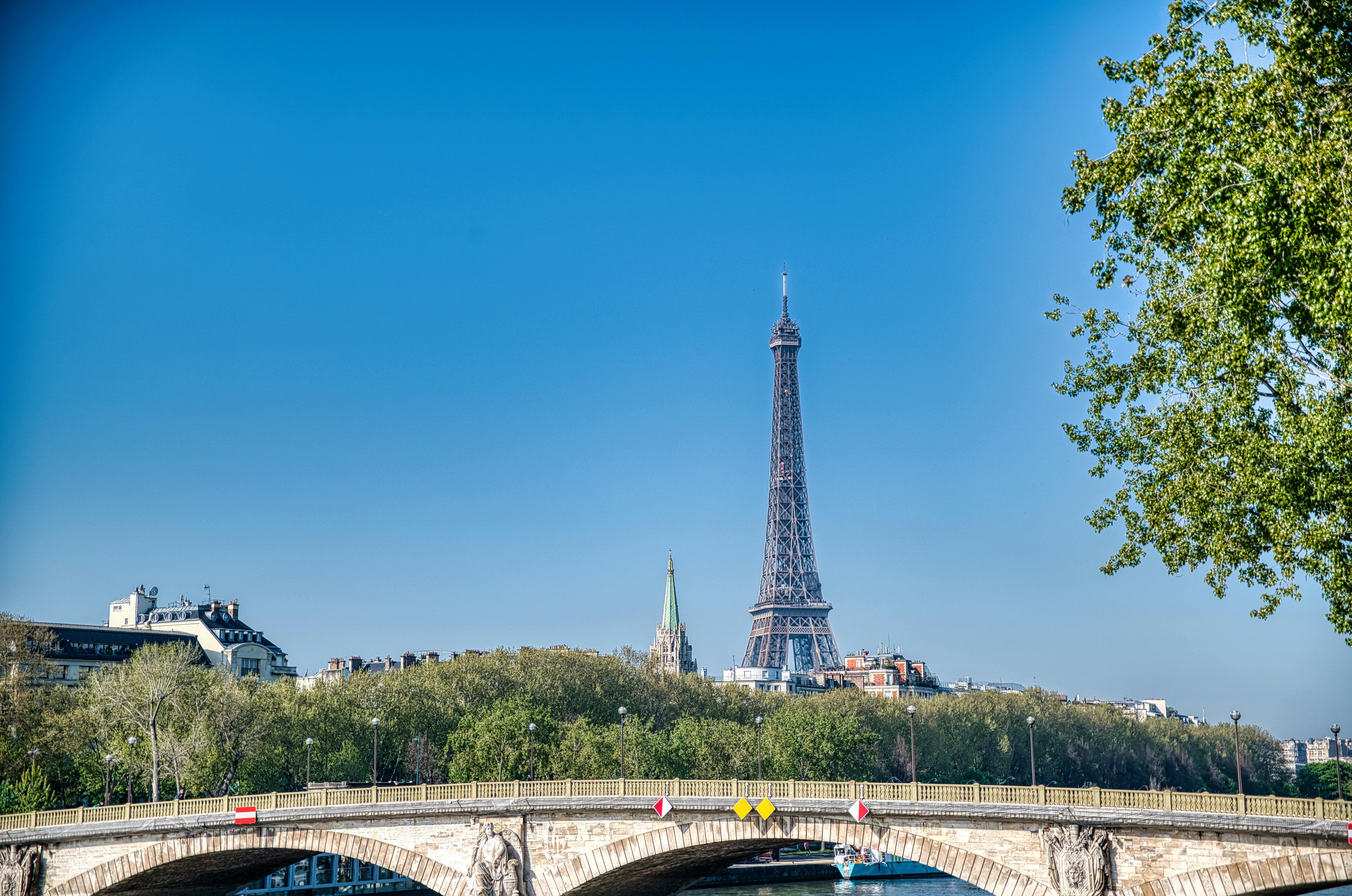 View of the Eiffel Tower and Parisian bridge under a clear blue sky in Paris, France.