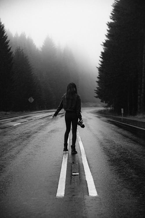 Grayscale Photo of a Woman Standing on the Road