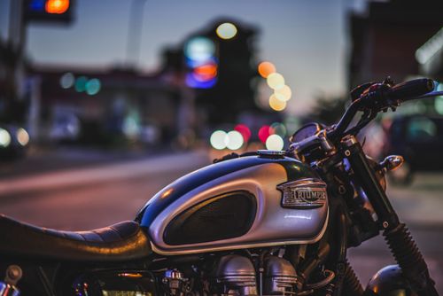 Free Dynamic close-up of a Triumph motorcycle parked on an illuminated city street at dusk. Stock Photo