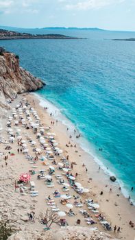 A stunning aerial view of a crowded beach with lounge chairs and umbrellas under the bright sun.