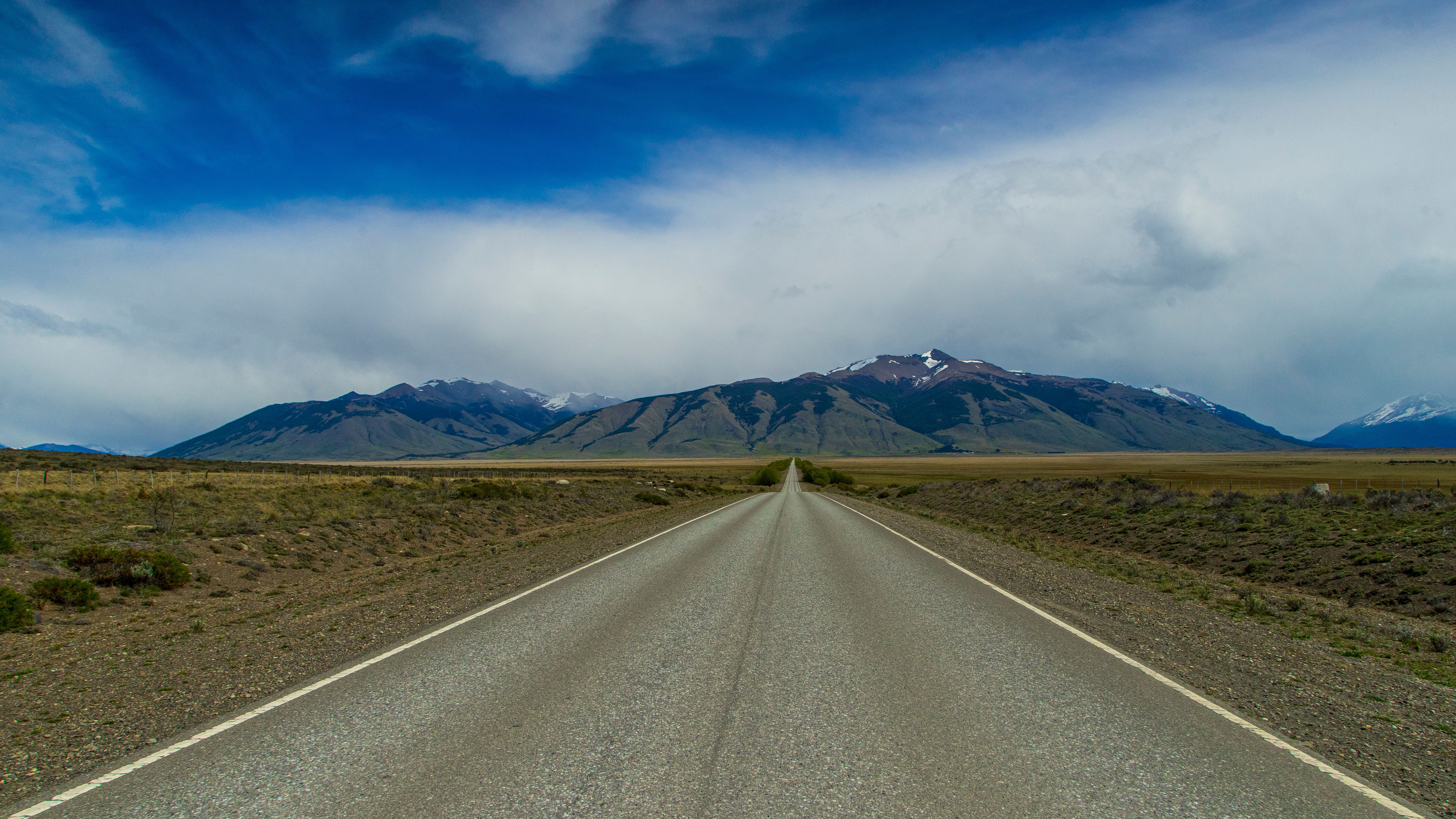 Straight road leading through Patagonian Andes under dramatic sky in Perito Moreno, Argentina.
