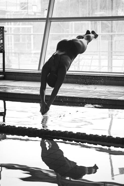 Grayscale Photo of a Woman Diving on the Water 