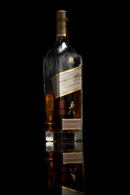 Free Elegant product photography of a premium gold label whisky bottle with reflection. Perfect for liquor branding. Stock Photo