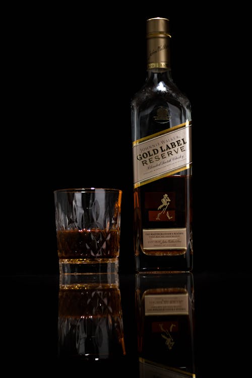 Close-Up Shot of Whiskey Glass and Bottle on Black Background