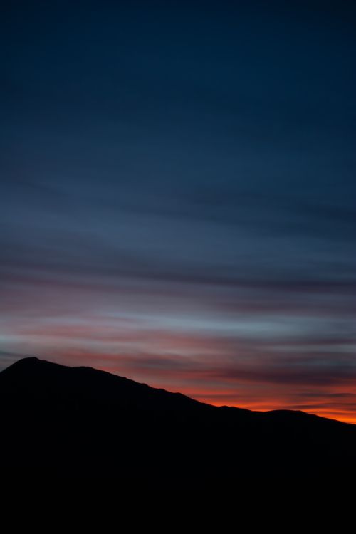 Free A stunning mountain silhouette against a colorful twilight sky, capturing the beauty of nature. Stock Photo