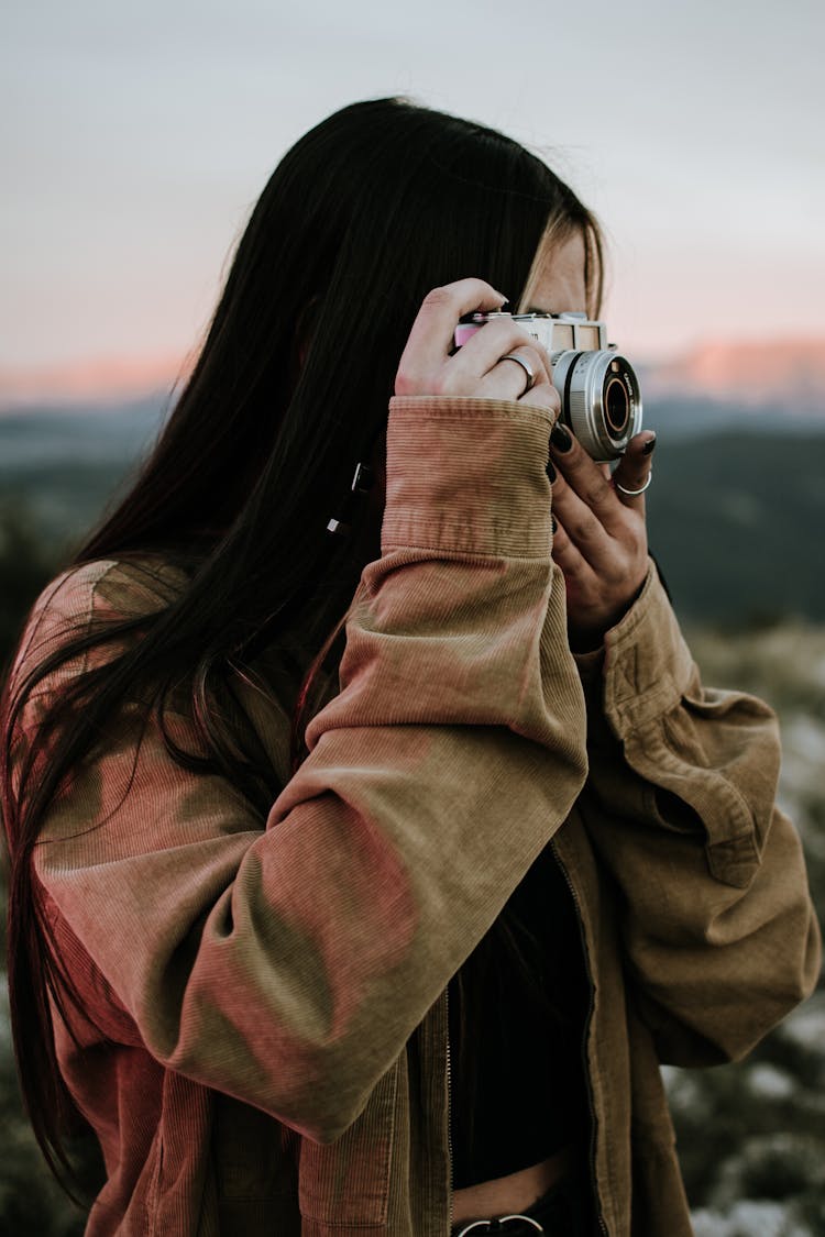 Woman In Brown Jacket Taking Photos Using Camera