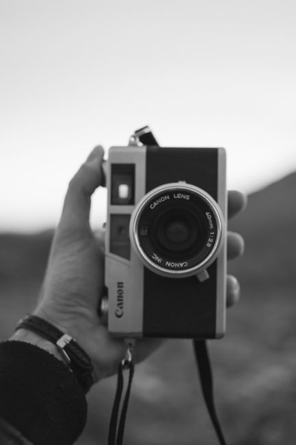 Monochrome image of a person holding a vintage camera, emphasizing classic photography feel.