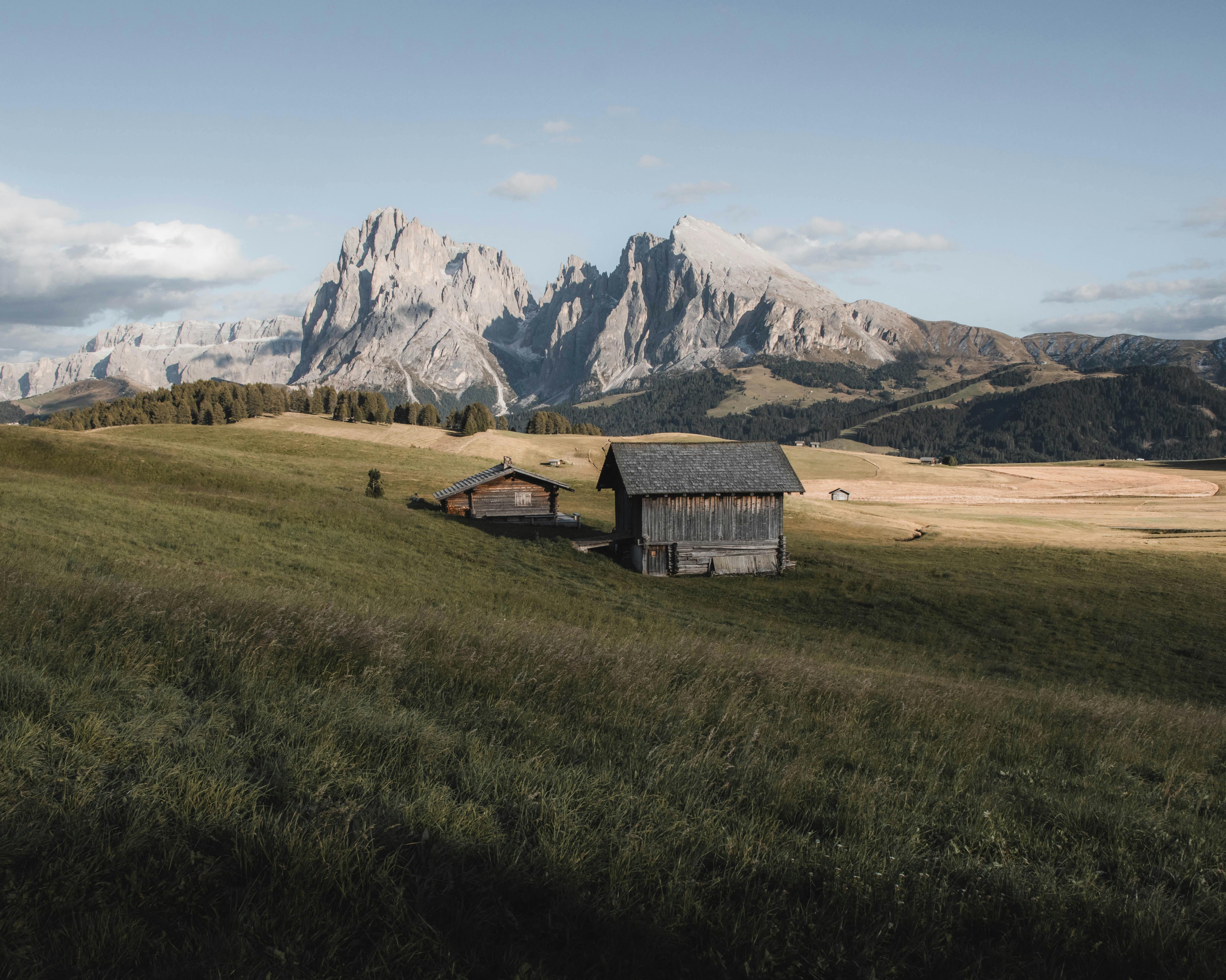 Stunning view of wooden cabins in Seis am Schlern, Trentino-South Tyrol, with the majestic Dolomites.