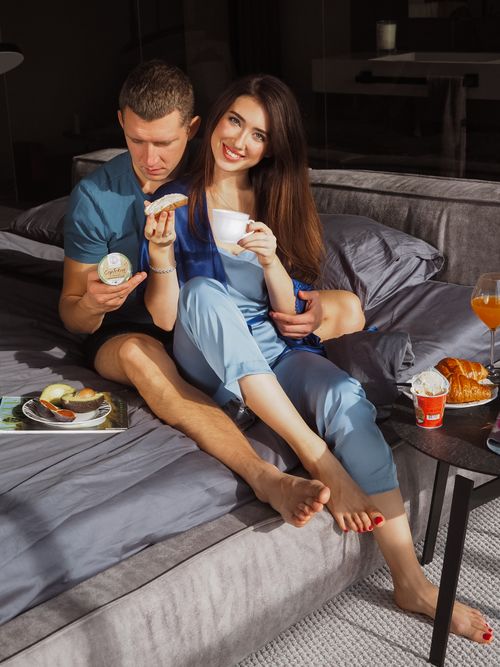 Free Caucasian couple enjoying breakfast in bed, exuding romance and relaxation. Stock Photo