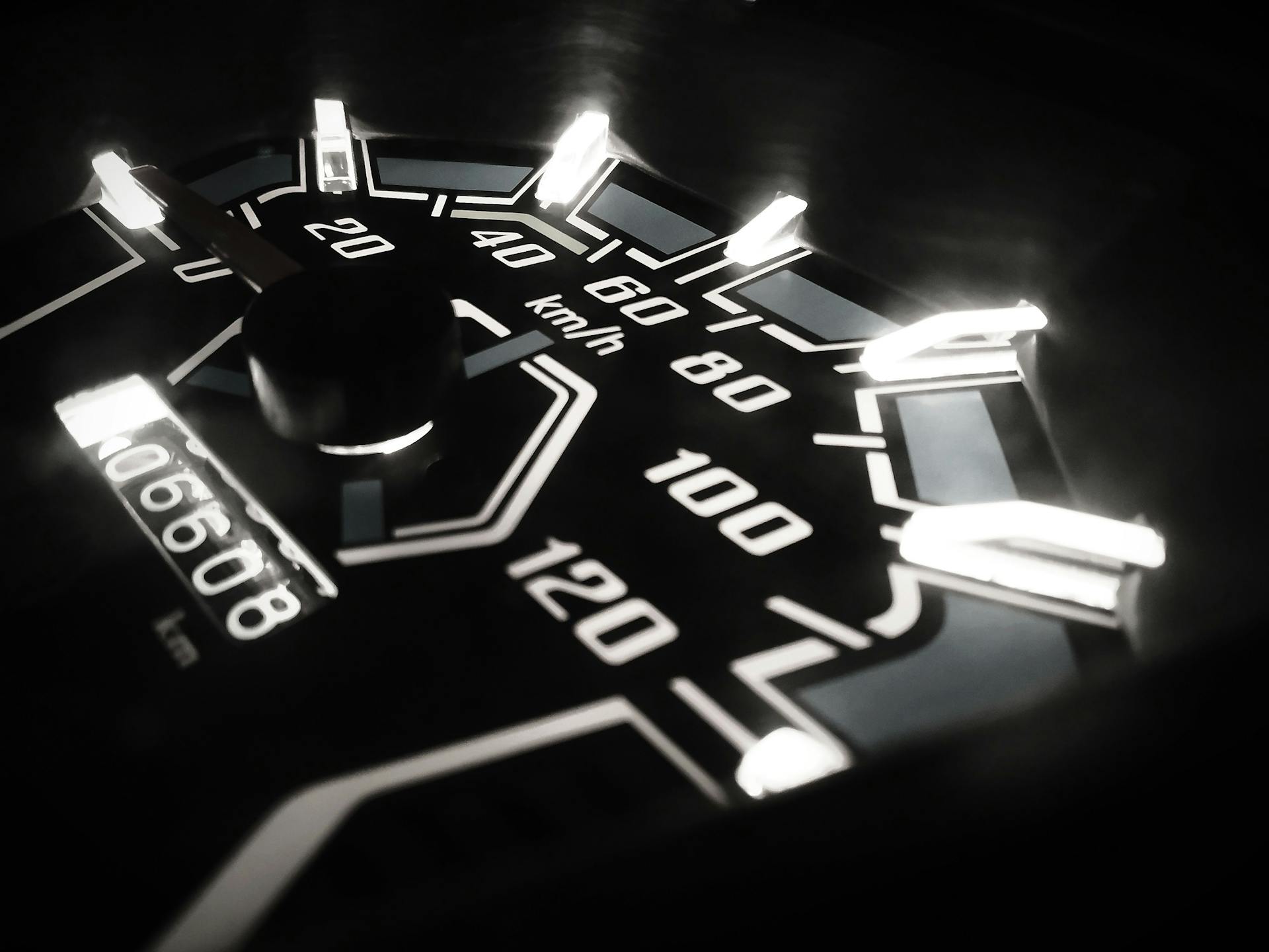 A close-up shot of an illuminated speedometer displaying km/h in a vehicle, captured at night in Pune.