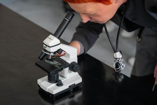 Scientist closely examining a slide under a microscope in a laboratory.