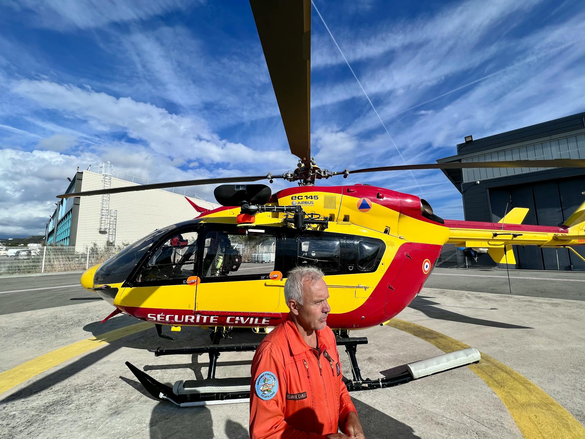 Pilot in Front of a Civil Security Helicopter Standing on a Helipad