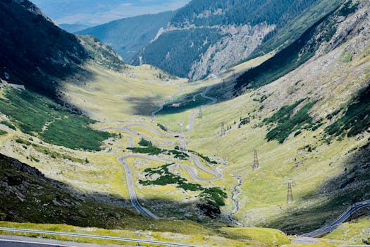A winding road through lush valleys and rugged mountains in Buda, Romania. Perfect for nature lovers.