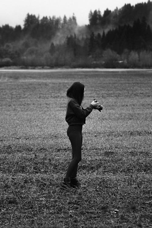 Monochrome Photo of Woman Holding a Camera 