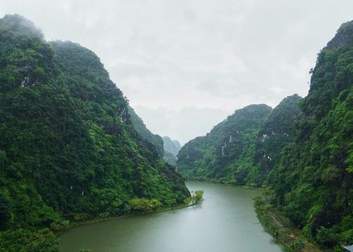 Free Lush green mountains with a tranquil river flowing between them, creating a serene natural landscape. Stock Photo