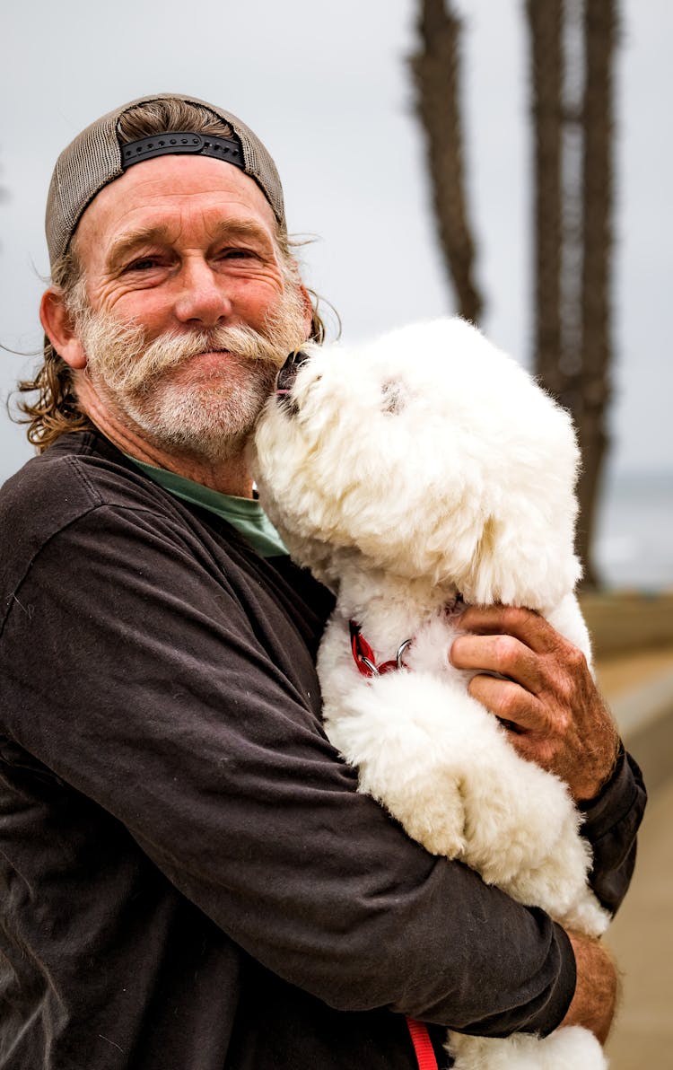 A Bearded Man Holding A White Toy Poodle