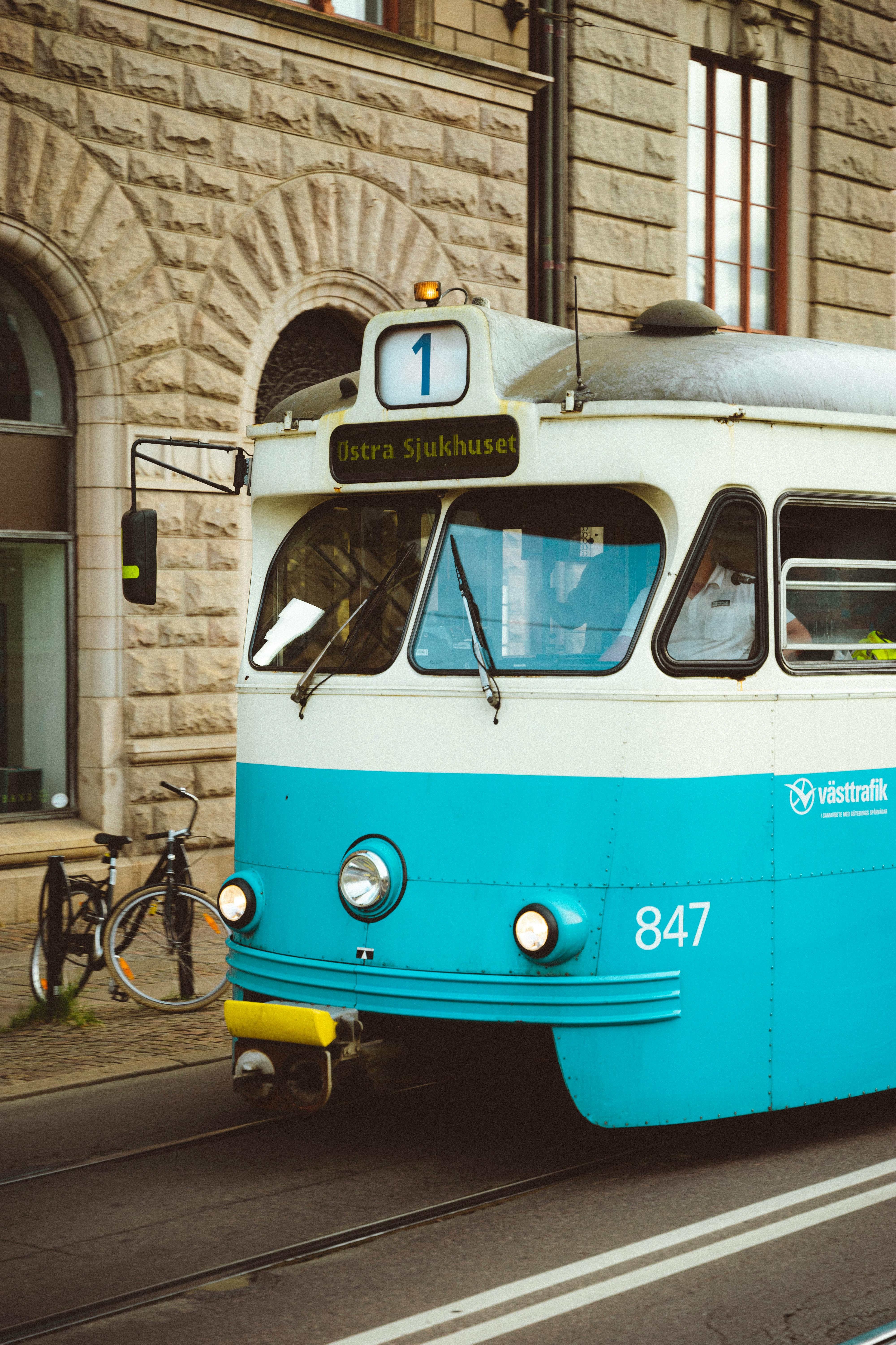 Urban scene featuring a vintage blue tram in motion with stone building backdrop.