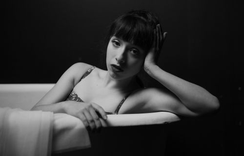 Free Artistic black and white portrait of a young woman in a bathtub, conveying elegance and emotion. Stock Photo