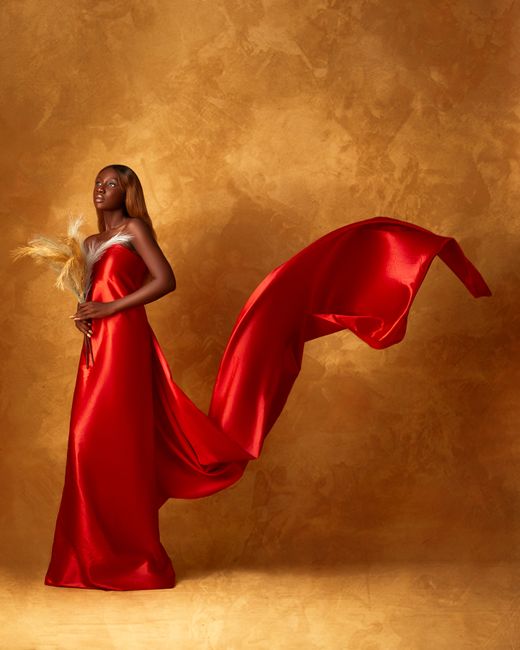 Stunning portrait of a woman in an elegant red dress against a textured backdrop.