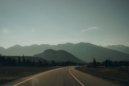 Scenic view of a highway leading to mountains under a clear sky.