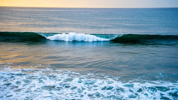 Serene ocean waves gently crashing on the beach at sunrise, capturing a tranquil moment in nature.