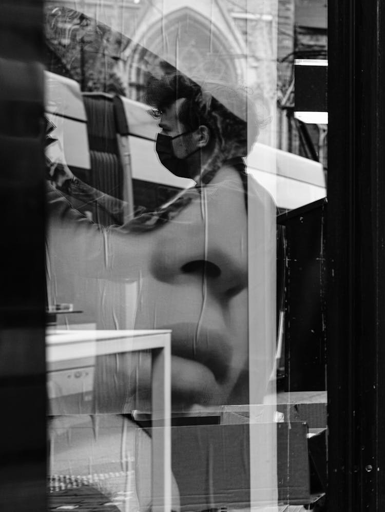 Reflection On A Man In A Shop Exposition Window With A Poster Of A Woman 