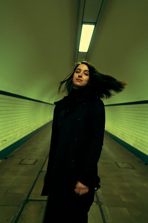 A Woman Wearing a Black Coat Standing on the Hallway