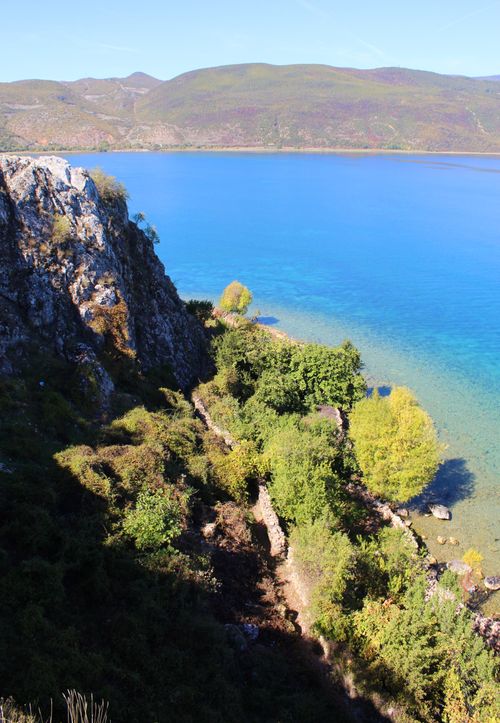 Free Beautiful rocky coastline with lush greenery and crystal blue waters under a clear sky. Stock Photo
