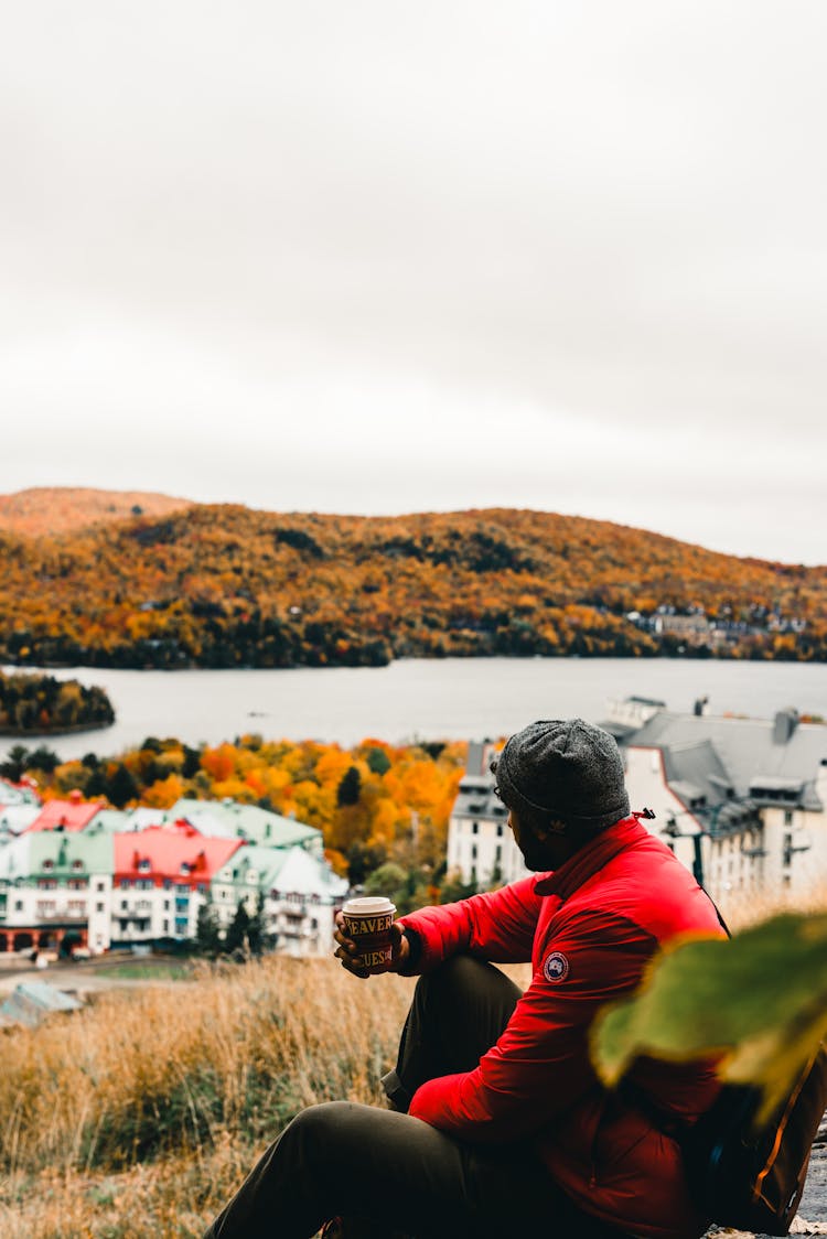 A Man Wearing Red Jacket While Drinking Coffee