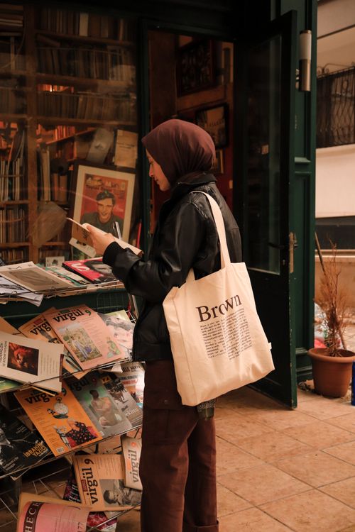 Free A woman in a hijab browsing magazines at a bookstore in Ankara, Turkey, carrying a tote bag. Stock Photo