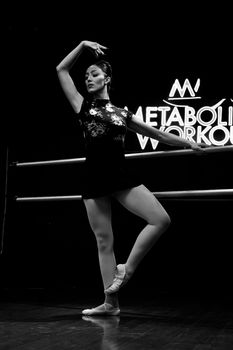 Elegant black and white photo of a ballerina performing a ballet pose in a studio.