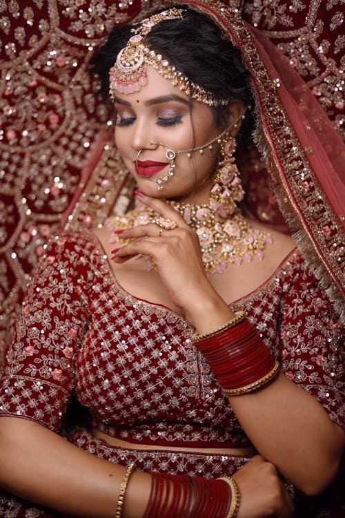 Photo of a Woman Wearing a Traditional Red Embroidered Dress and Golden Jewellery