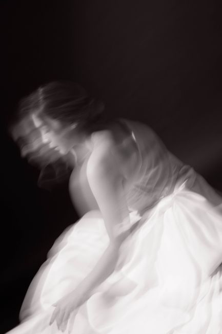 Elegant black and white blurred motion portrait of a woman in a dress.