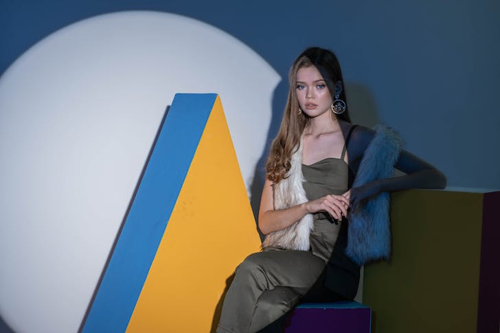 Woman in White Long Sleeve Shirt and Black Pants Sitting on Blue and Yellow Chair