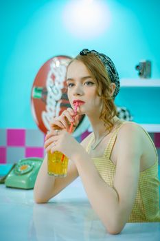 Stylish woman sipping a drink in a retro-themed soda shop.