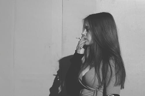 Grayscale Photo of a Woman Smoking Cigarette