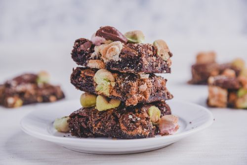 Free Delicious chocolate brownies with nuts and marshmallows stacked on a plate. Perfect indulgence! Stock Photo