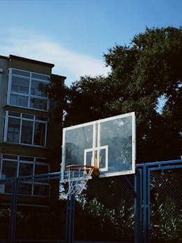A basketball hoop set outdoors in front of a residential building under a clear blue sky.