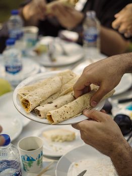 Tasty pita wraps being served at an outdoor picnic with bottled water and plates.