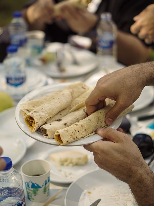 Free Tasty pita wraps being served at an outdoor picnic with bottled water and plates. Stock Photo